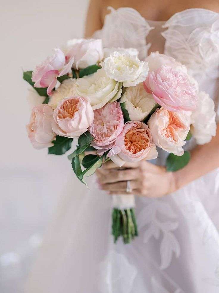 Bride holding a round bouquet of blush, peach and white garden roses