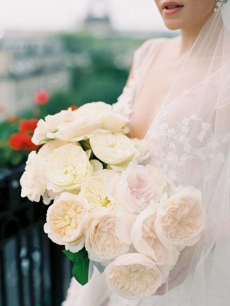 Bride on a Paris balcony holding ivory and blush garden roses