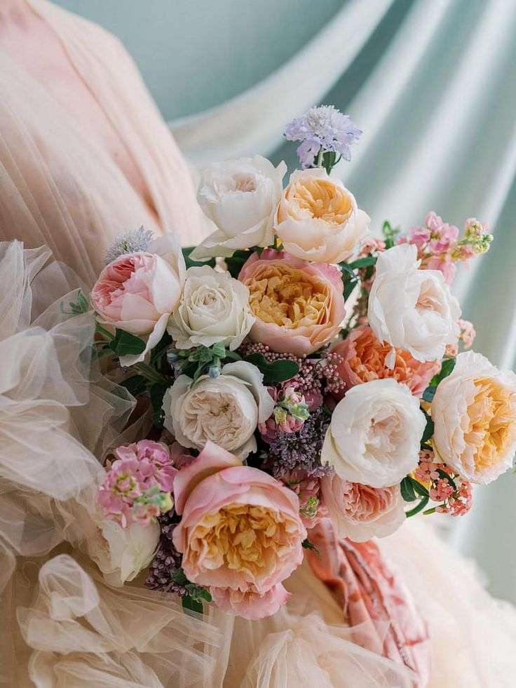 Tightly packed bouquet of peach and blush garden roses with lilac accents