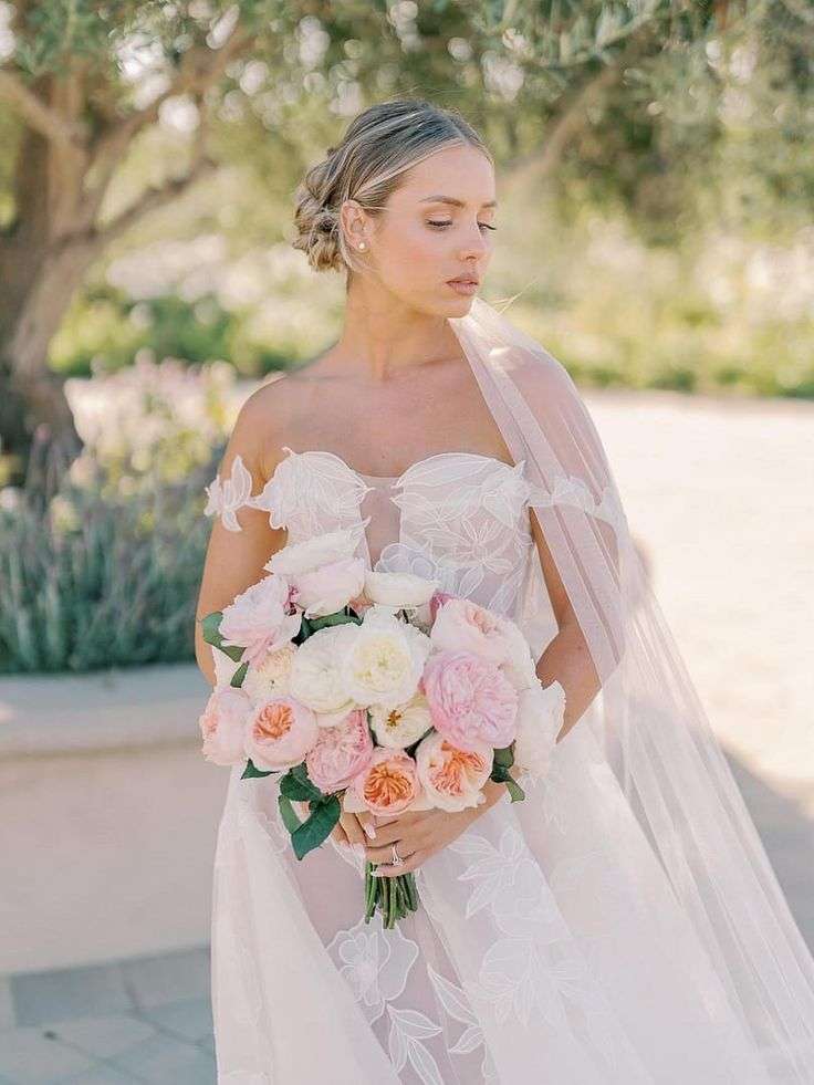 Veiled bride outdoors holding a blush and ivory garden rose bouquet