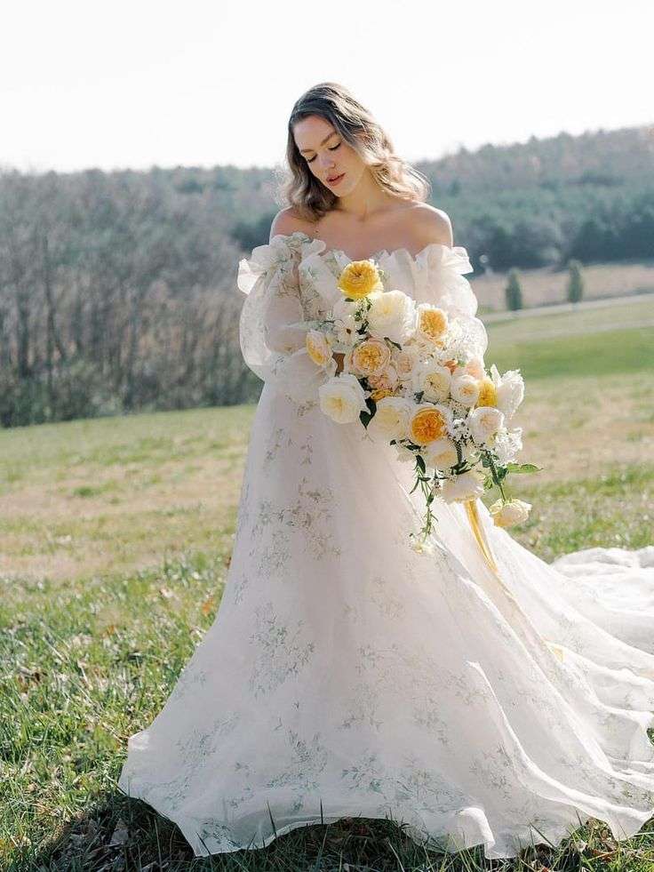 Bride walking through a sunlit field with a cascading yellow garden rose bouquet