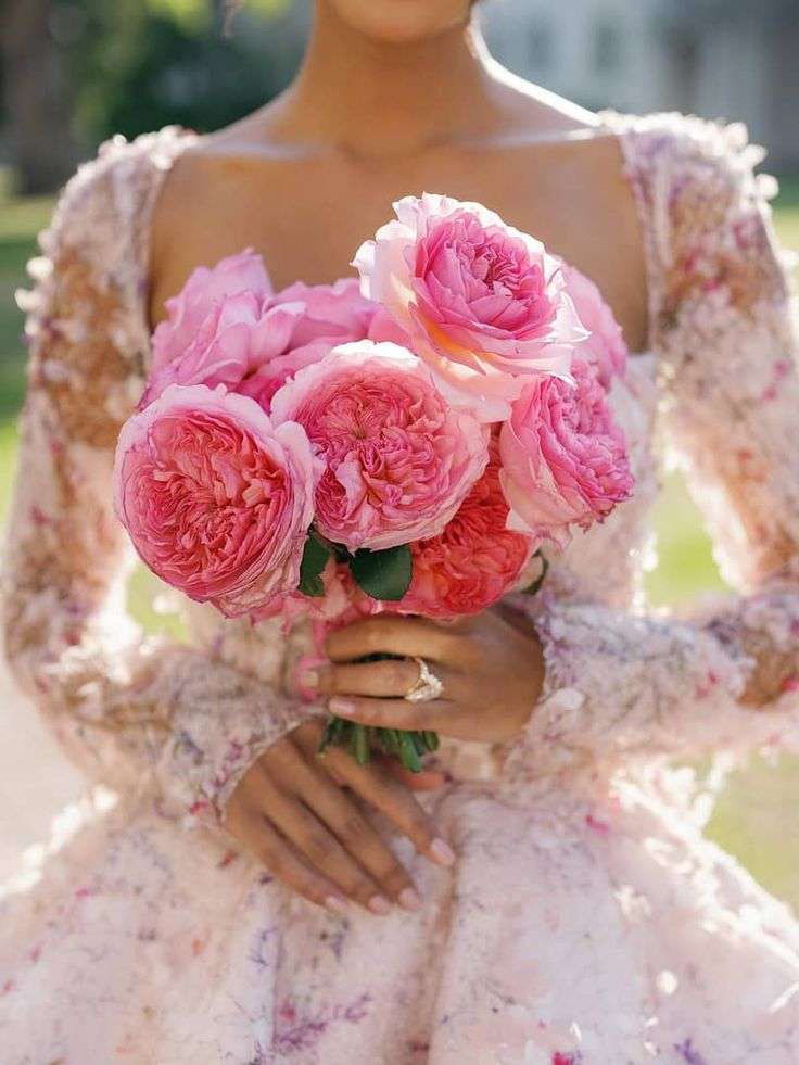Bride in a floral gown holding a compact bouquet of hot pink garden roses