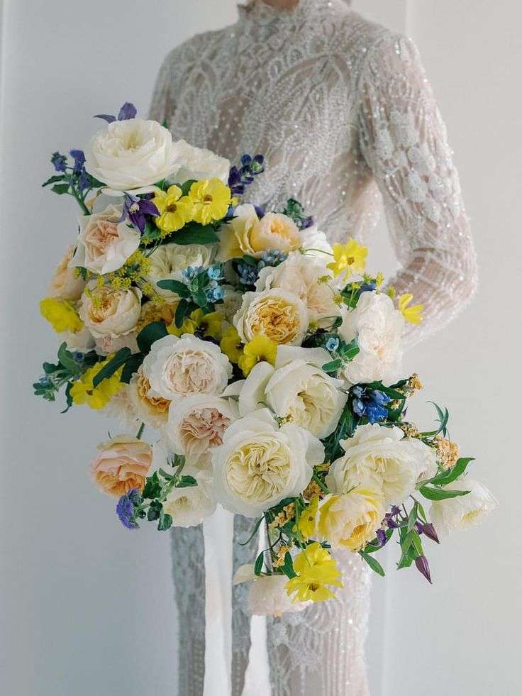 Cascading bouquet of ivory garden roses with yellow wildflowers and blue accents
