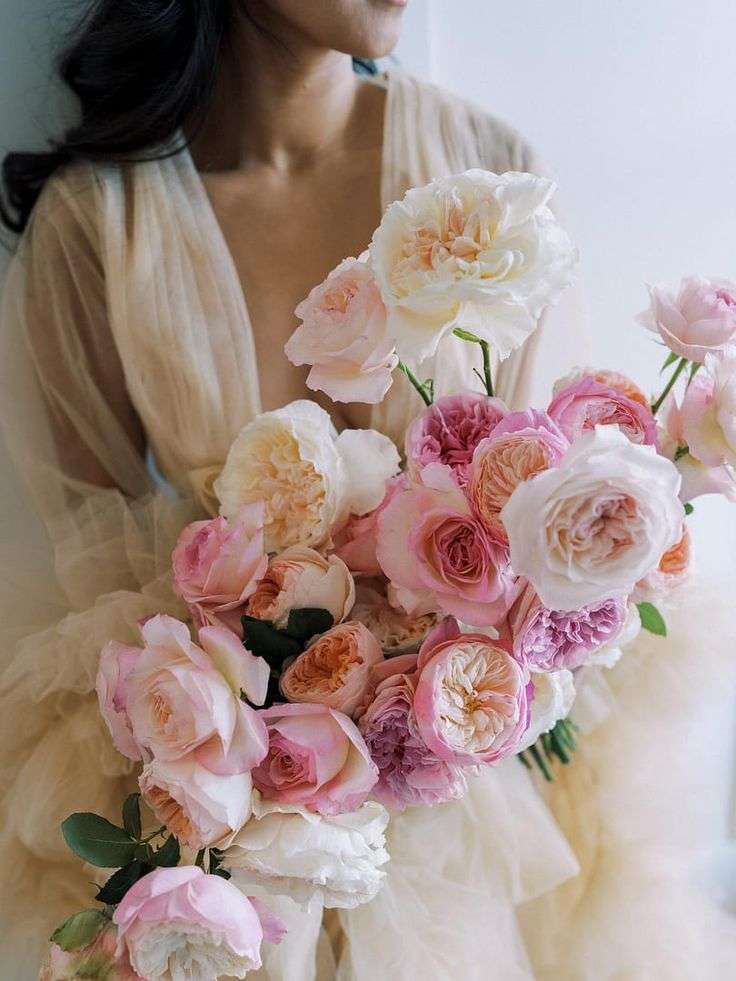 Asymmetrical pastel bouquet of pink and blush garden roses against a flowing gown
