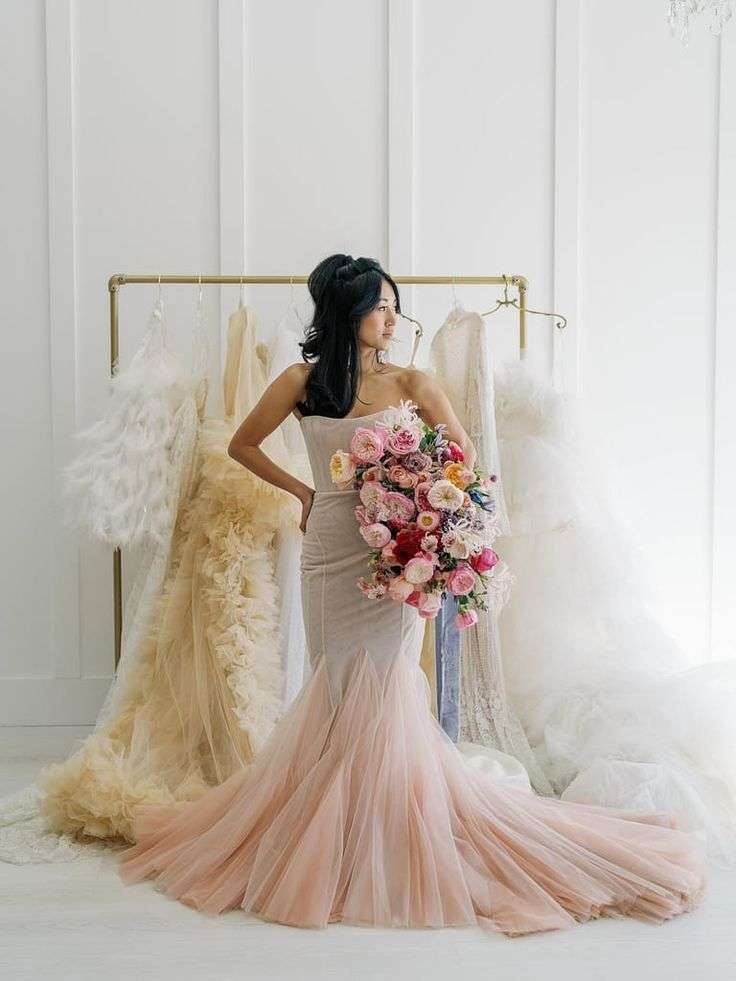 Bride in a blush gown holding a vivid pink and fuchsia garden rose bouquet