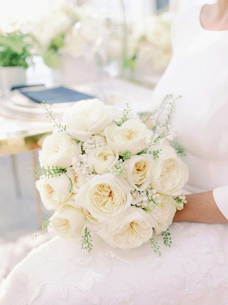 Compact bouquet of white garden roses and delicate greenery on a reception table