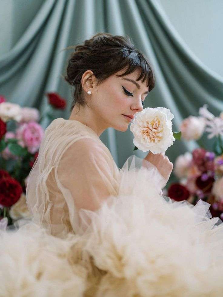 Bride in tulle gown smelling a single cream David Austin garden rose