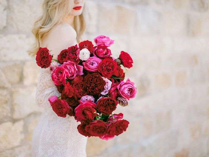 Bride carrying an oversized bouquet of deep red and hot pink garden roses