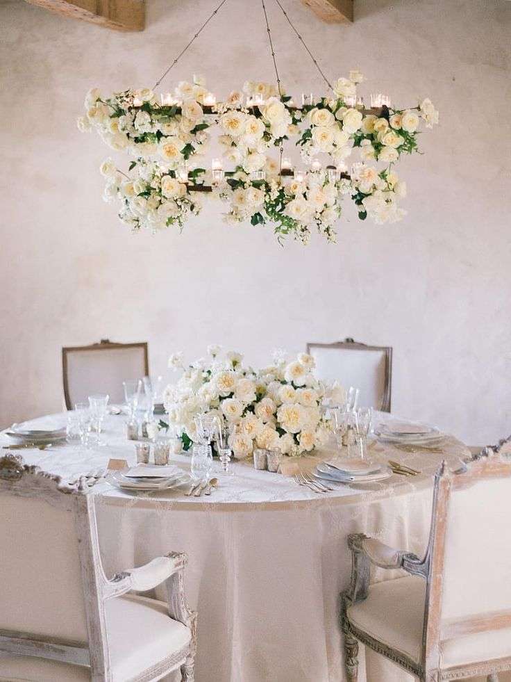 Suspended floral chandelier of ivory garden roses over a rustic reception table