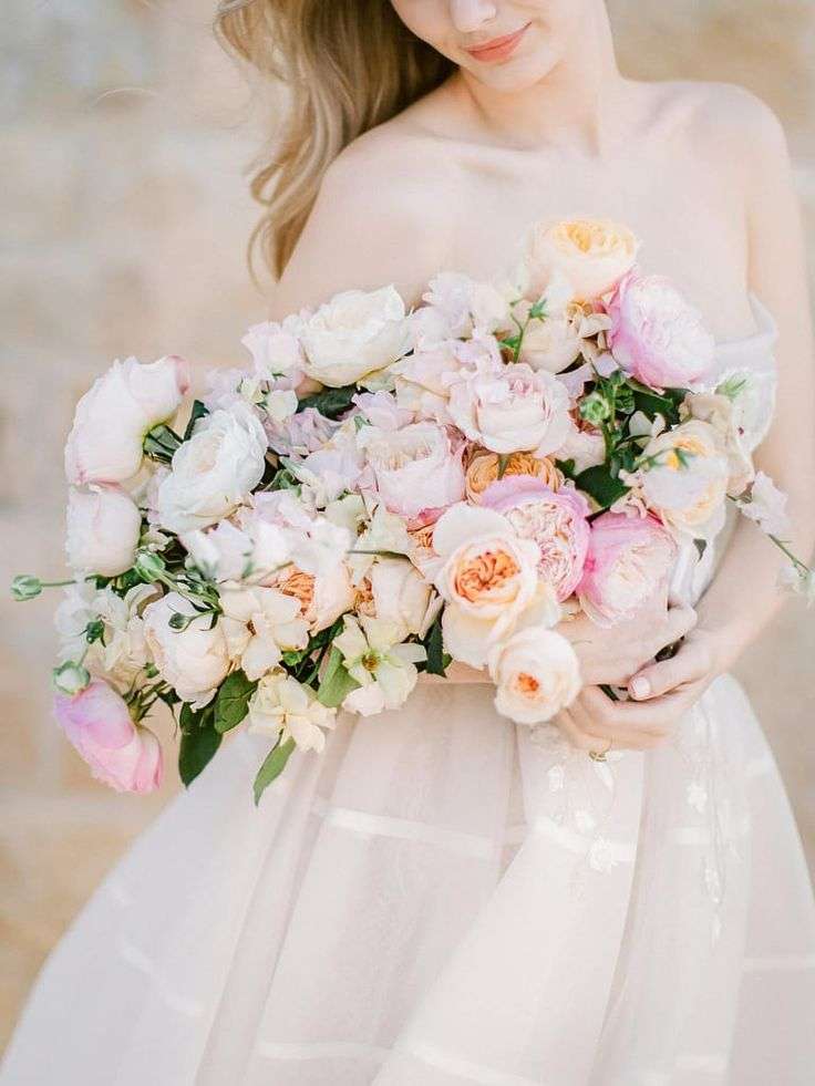 Bride holding a lush bouquet of blush and ivory garden roses