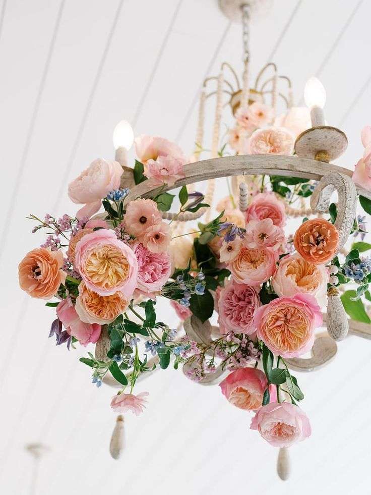 A hanging arrangement of peach and pink garden roses suspended from a white beamed ceiling.